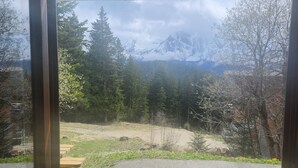 Una terraza de madera con vistas a un paisaje montañoso, una mesa de picnic y un área de grava.