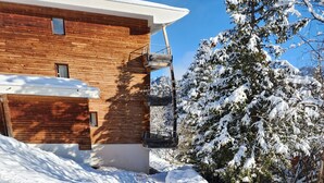 Una cabaña de madera con terraza de madera y un paisaje nevado.
