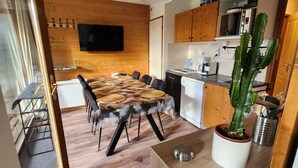 Cocina moderna con armarios de madera, microondas integrado y zona de comedor con mesa y sillas redondas.