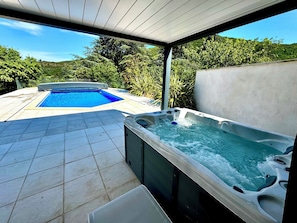 A swimming pool and a hot tub in an outdoor setting.