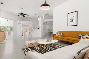 A modern living room with a sofa, a coffee table, and a dining area with chairs.