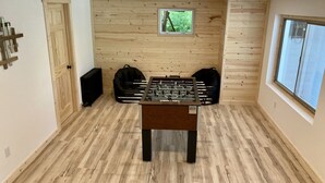A room with a wooden floor, a foosball table, a window, and a radiator.