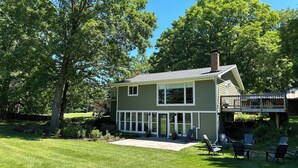 A two-story house with a deck, surrounded by a well-maintained lawn and trees.