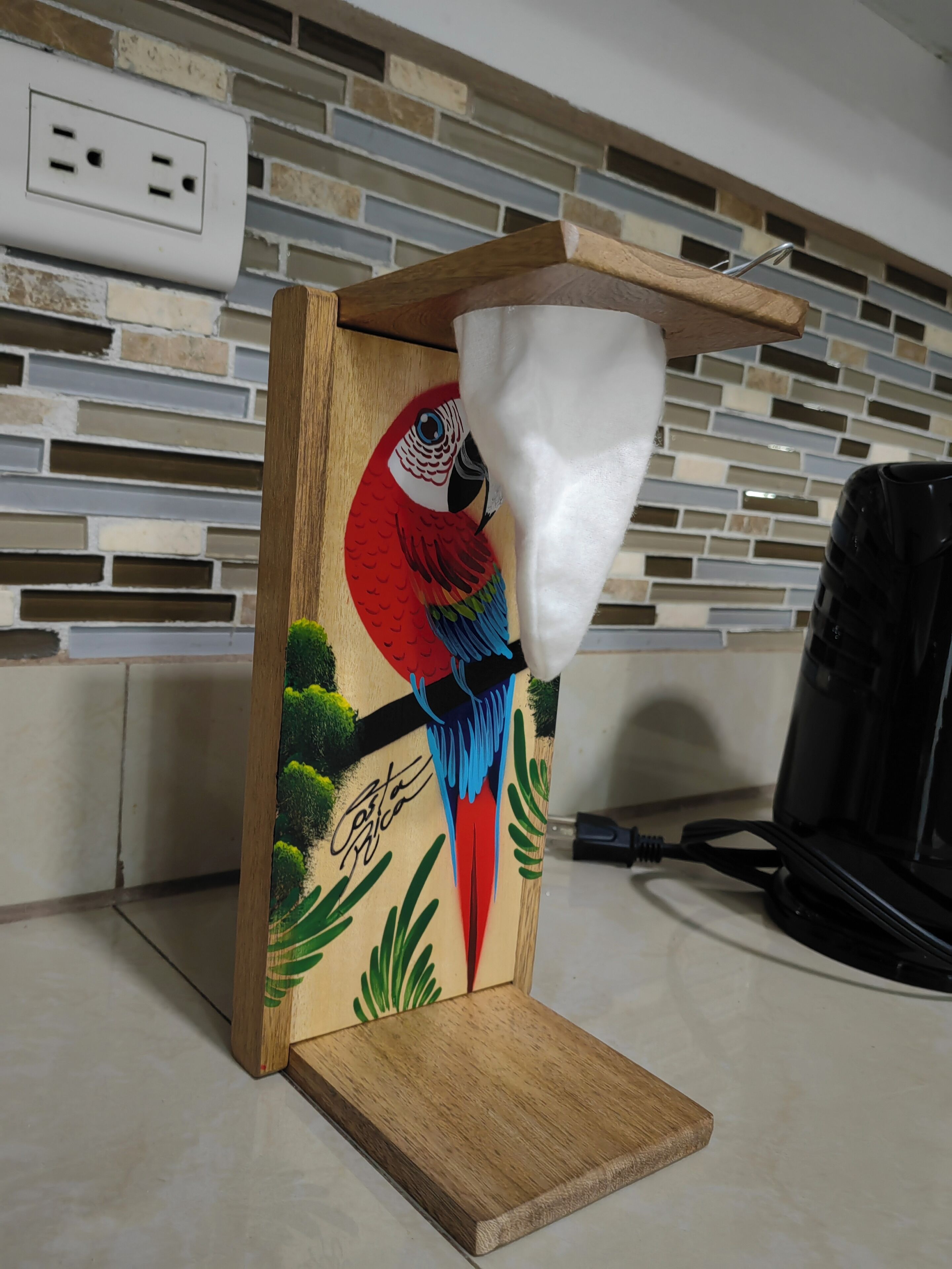 A wooden kitchen counter with a parrot-themed soap dispenser.