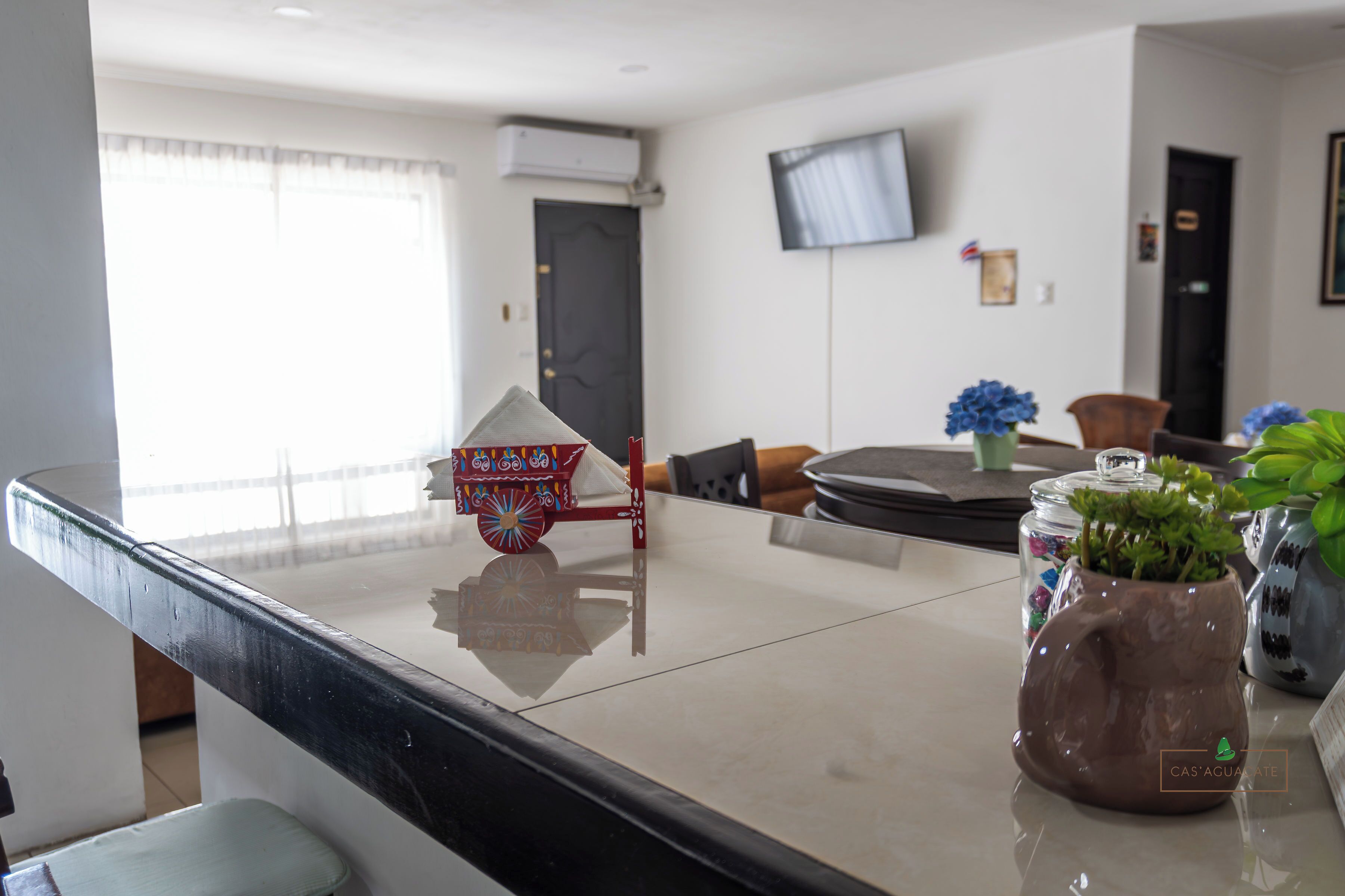A modern kitchen with a marble countertop, a small decorative cart, and a potted plant.