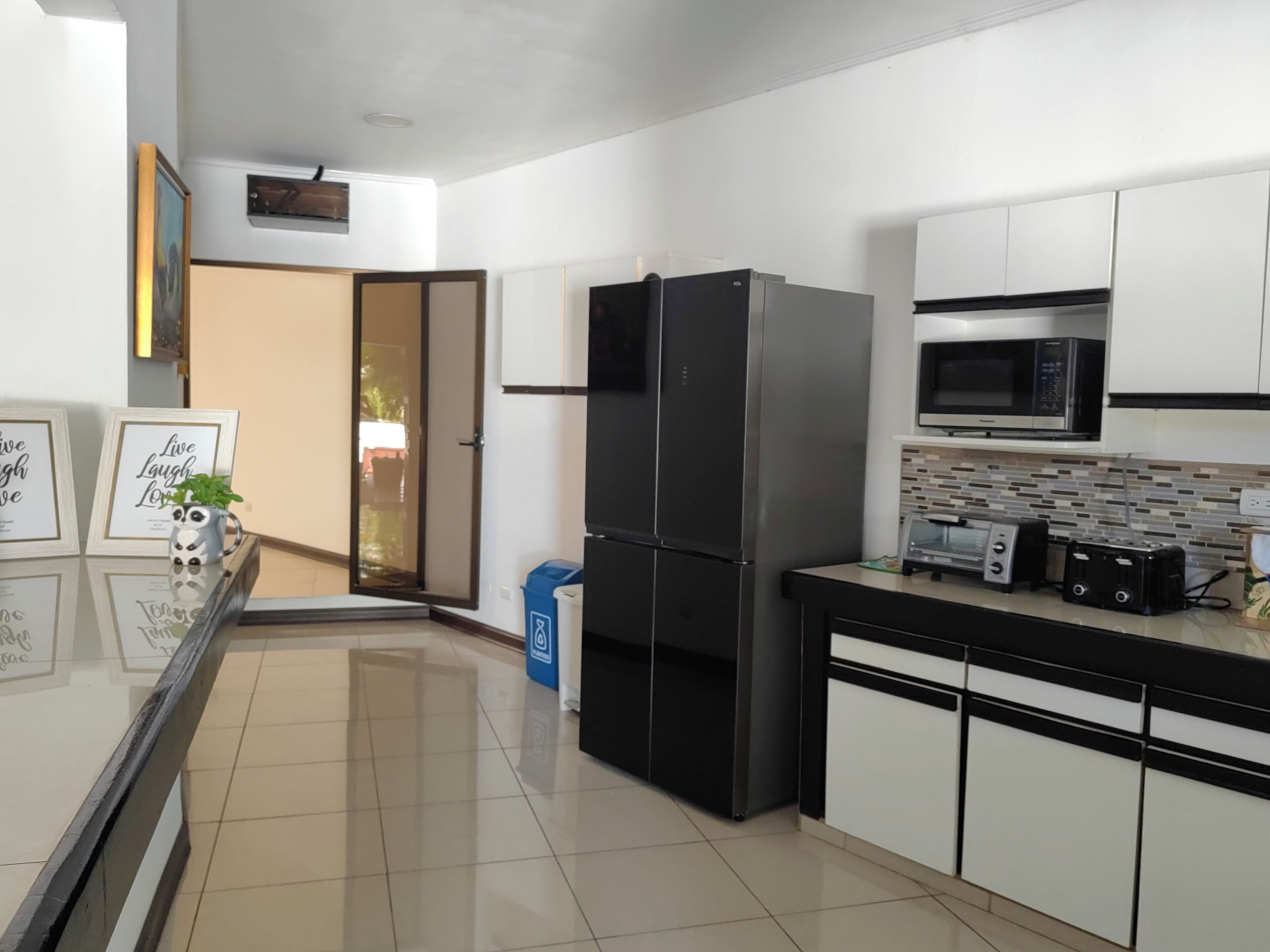 A modern kitchen with a black refrigerator, a microwave, and a toaster on the counter.