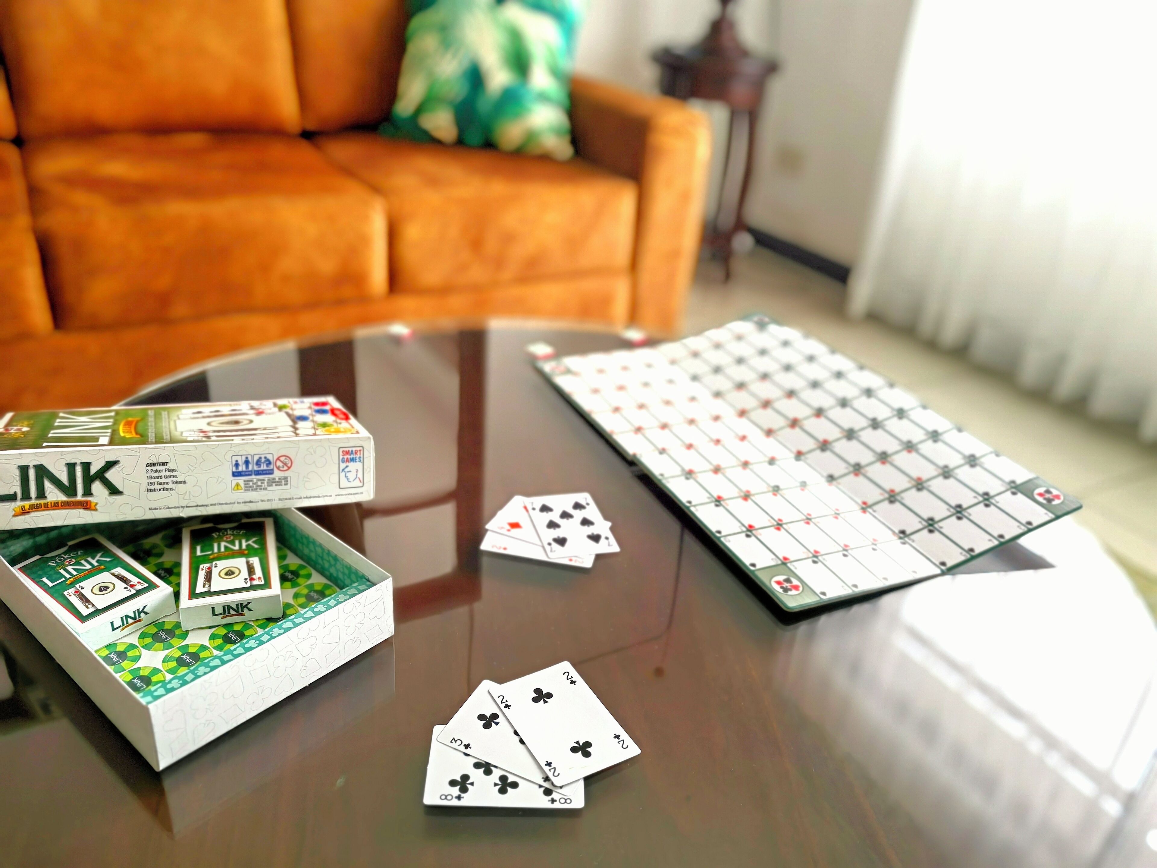 Jogo de tabuleiro Link sobre uma mesa de vidro, com cartas de baralho.