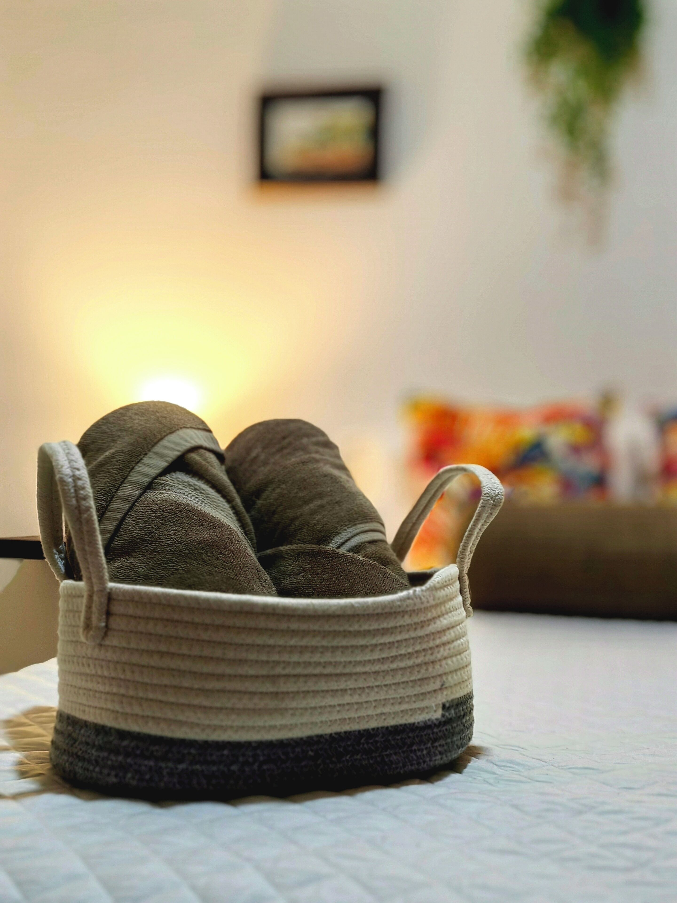 A basket with shoes on a bed.