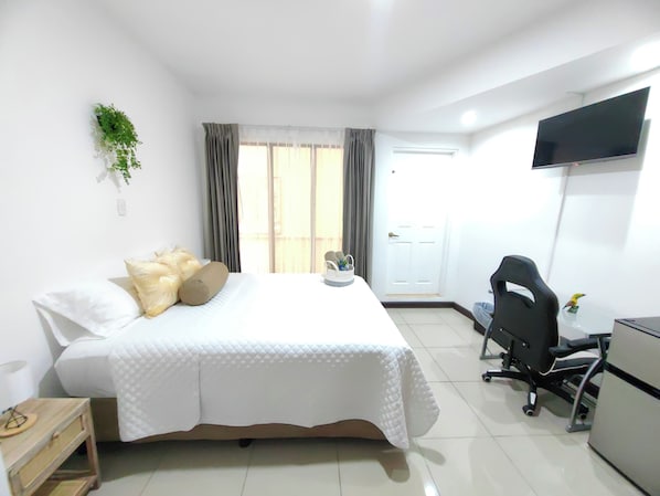 A hotel room with a bed, a desk, a chair, a TV, and a window with curtains. - Hotel Boutique CasAguacate (La Asuncion)