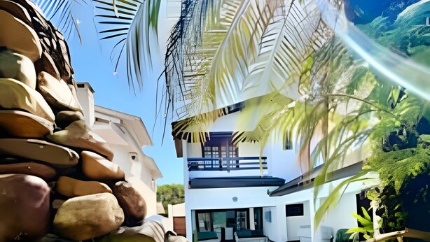 Una casa moderna con piscina, rodeada de follaje y rocas.