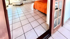 Una habitación amplia con una cama, un banco y un ventanal.
