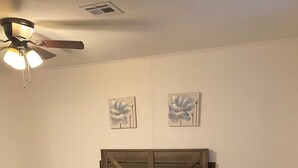 Une chambre à coucher avec un lit, une chaise, une table de chevet et un ventilateur de plafond.