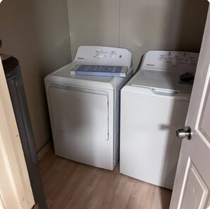 Une buanderie avec deux machines à laver blanches et une poubelle.