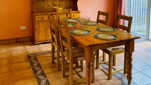 A dining area with a wooden table, chairs, and a wooden cabinet with shelves. - Convenient Spacious 3 Bedroom Home in Kenmare Town (Kenmare)