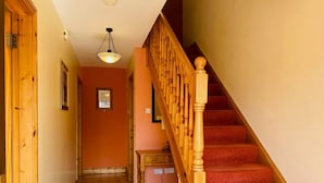 A wooden staircase with red carpeted steps leading to a landing. - Convenient Spacious 3 Bedroom Home in Kenmare Town (Kenmare)