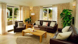 A spacious living room with a brown leather sofa, a wooden coffee table, and a large potted plant.