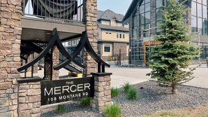 A building with a stone facade, a sign reading "The Mercer 108 Montane Rd.", and a small Christmas tree in the foreground.