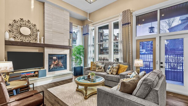 A spacious living room with a fireplace, comfortable seating, and large windows offering a view of the outside.