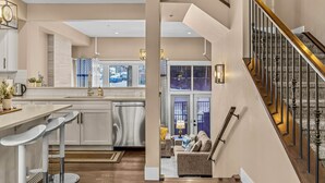 A spacious kitchen with modern appliances, a bar area, and a staircase leading to a living area.