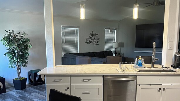 A modern kitchen with white cabinets, a built-in dishwasher, and a large window with blinds. - Charming 3-bedroom house with AC, WiFi in pleasant San Antonio (San Antonio)