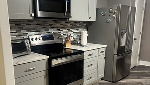 A modern kitchen with stainless steel appliances, a tiled backsplash, and a herringbone wood floor. - Charming 3-bedroom house with AC, WiFi in pleasant San Antonio (San Antonio)