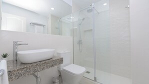 Un bagno moderno con un ampio lavandino bianco, un box doccia in vetro e un WC.