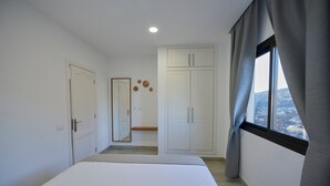 Una camera da letto con un letto, un armadio, uno specchio e una finestra con tende.