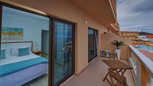 A balcony with a bed, a potted plant, and a view of a swimming pool.