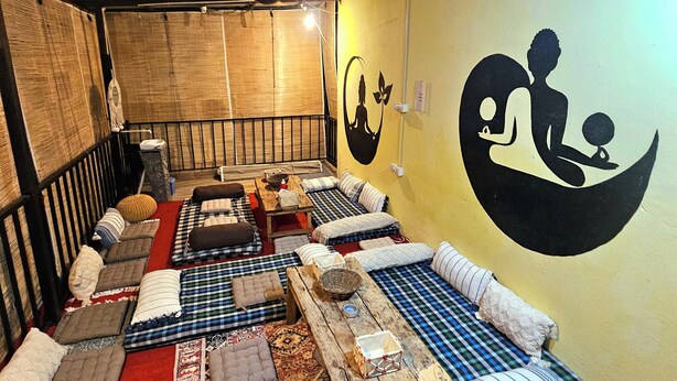 Una habitación con varias zonas de estar, que incluyen sofás y cojines, distribuidos sobre alfombras estampadas.