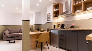 A modern kitchen with a dining area, a sofa, and a coffee table. - Mar25 #31 by Smart Cozy Suites (Athina)
