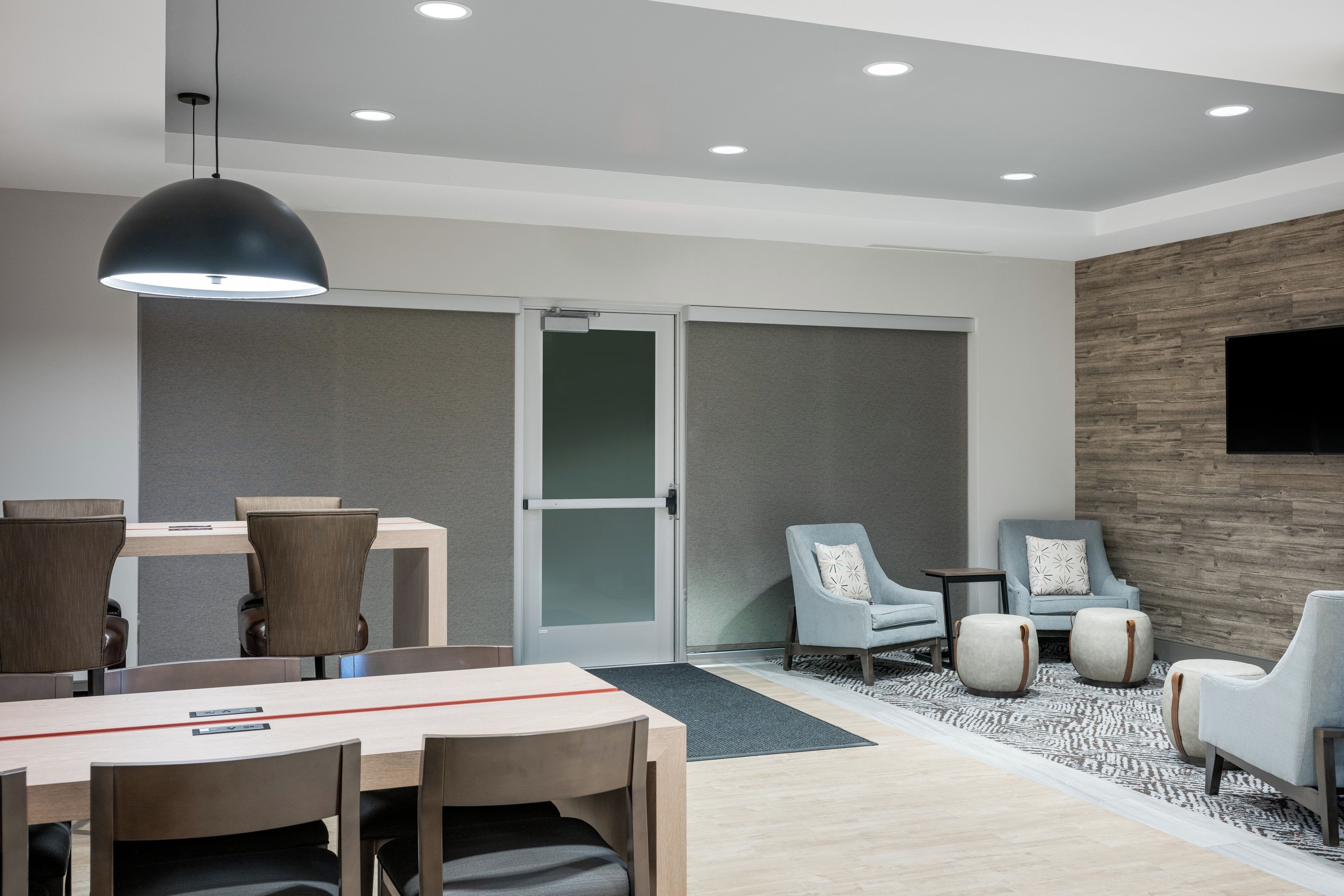 A modern hotel room with a dining area, seating, and a television.