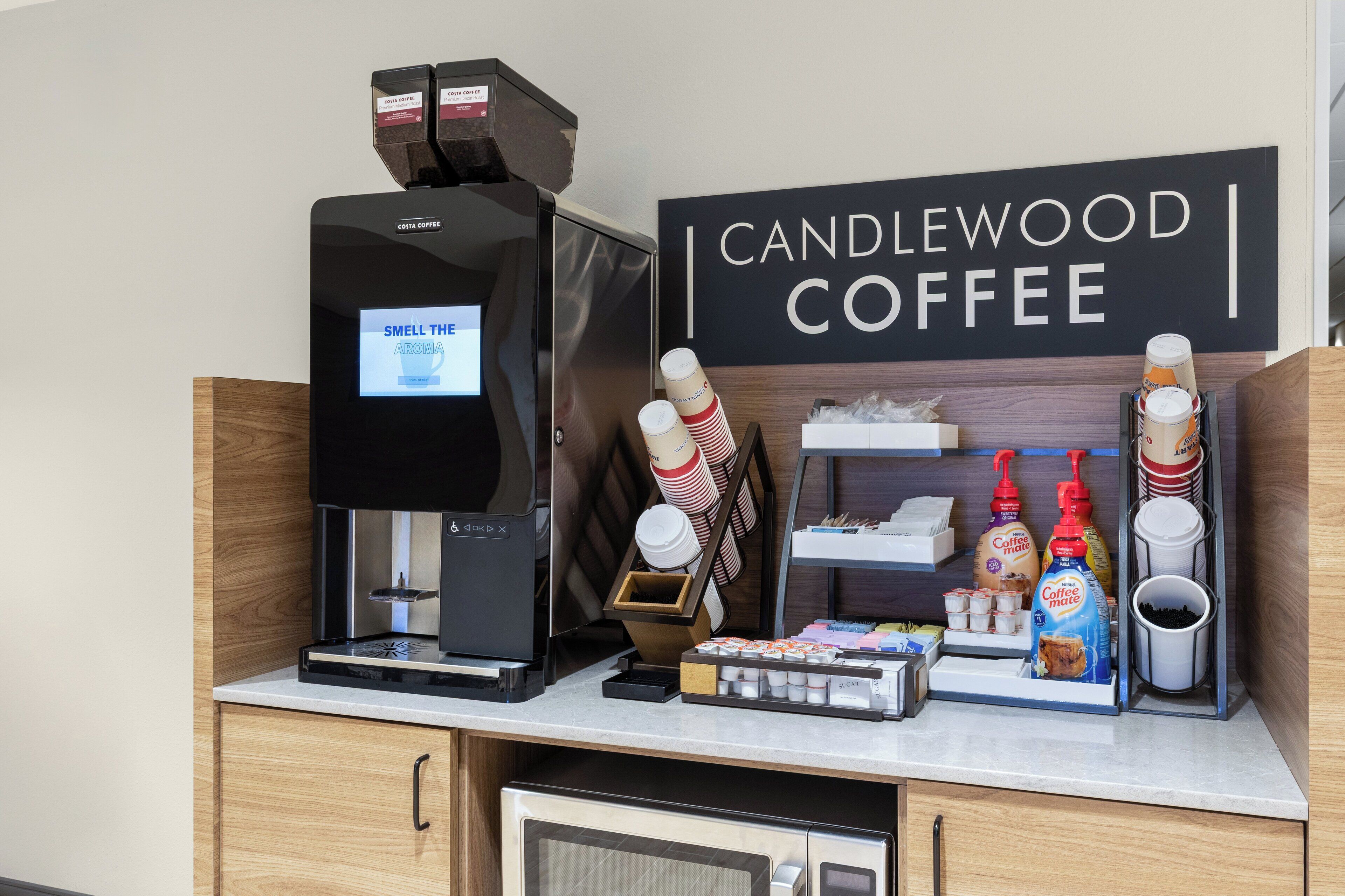 A coffee station with a coffee machine, disposable cups, and coffee pods.