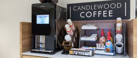 A coffee station with a coffee machine, disposable cups, and coffee pods.