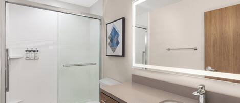 A modern bathroom with a glass shower enclosure, a toilet, a vanity with a mirror, and a sink.