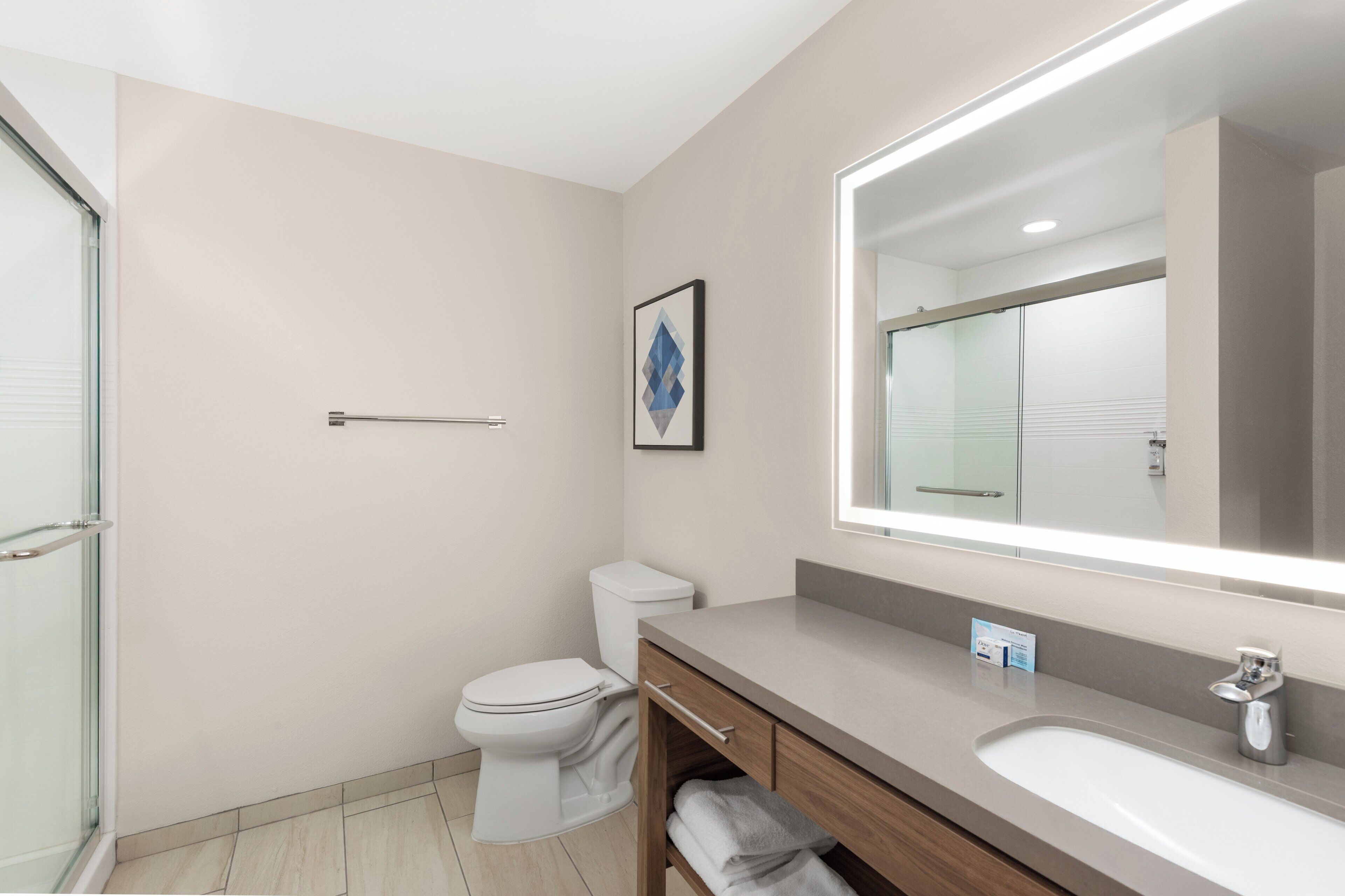 Un baño moderno con inodoro, lavamanos y un espejo grande.