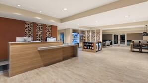 En moderne hotellobby med reception, siddeområde og en kiosk til forfriskninger.