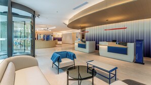 A modern hotel lobby with a reception desk, seating area, and glass walls offering views of the interior. - Holiday Inn Express Shanghai Hongqiao CBD by IHG (Shanghai)