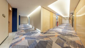 A modern hotel corridor with patterned carpet, wooden doors, and recessed lighting. - Holiday Inn Express Shanghai Hongqiao CBD by IHG (Shanghai)