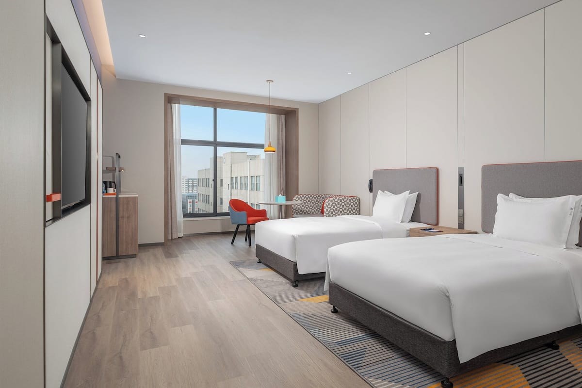 Une chambre d’hôtel moderne avec deux lits, un bureau et une chaise.