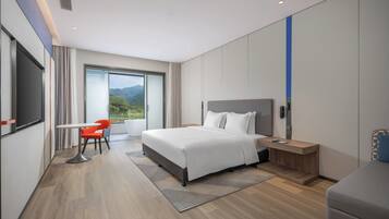 Una habitación de hotel moderna con una cama grande, un escritorio, una silla y vistas a las montañas.
