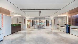 Un hall d’hôtel moderne comprenant un comptoir d’accueil, un espace salon et une vue sur la salle à manger.