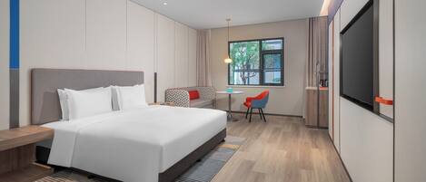 Ein Hotelzimmer mit Bett, Sitzecke, kleinem Tisch, Fernseher und Fenster mit Aussicht.