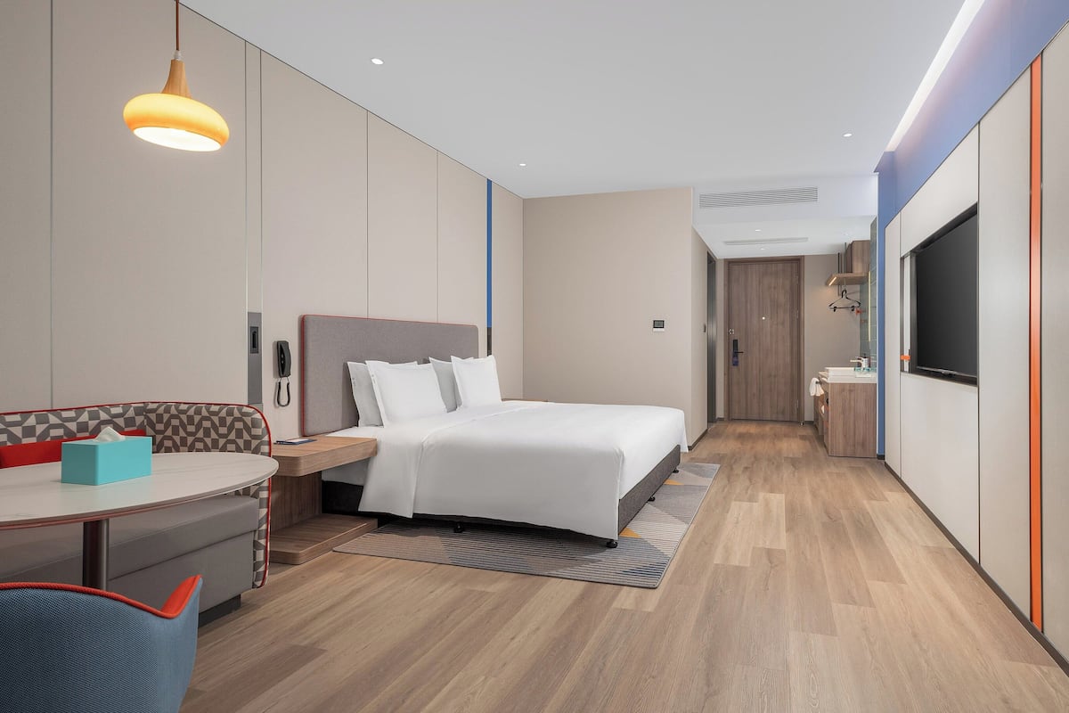 Une chambre d’hôtel moderne équipée d’un lit, d’une table de chevet et d’un bureau avec une chaise.