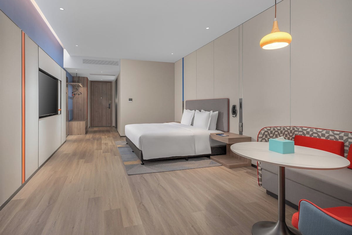 Une chambre d’hôtel moderne équipée d’un lit, d’une table de chevet et d’un coin salon avec une table et des chaises.
