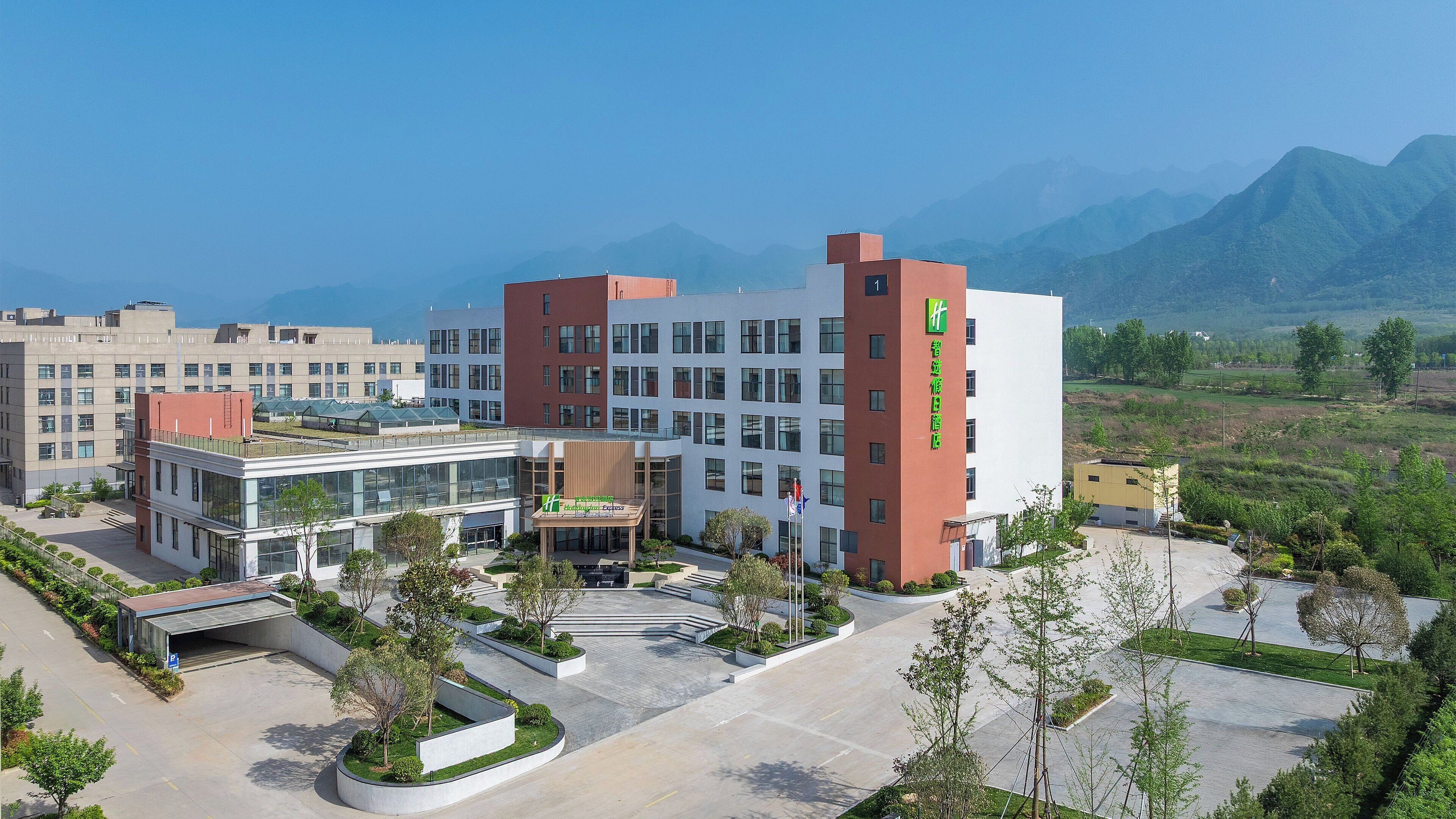 A modern building with a central courtyard, surrounded by greenery and a mountainous backdrop.