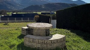 A stone bench in a grassy field with a mountain backdrop.
