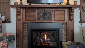 A living room with a fireplace, a television mounted above it, and two lamps on either side.