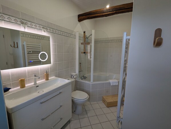 A bathroom with a white sink, mirror, toilet, and shower.