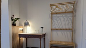 Une pièce avec un bureau en bois, une lampe, une plante et une étagère en bois.