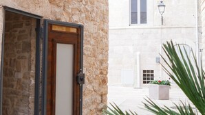 A stone building with a wooden door, a potted plant, and a street lamp.